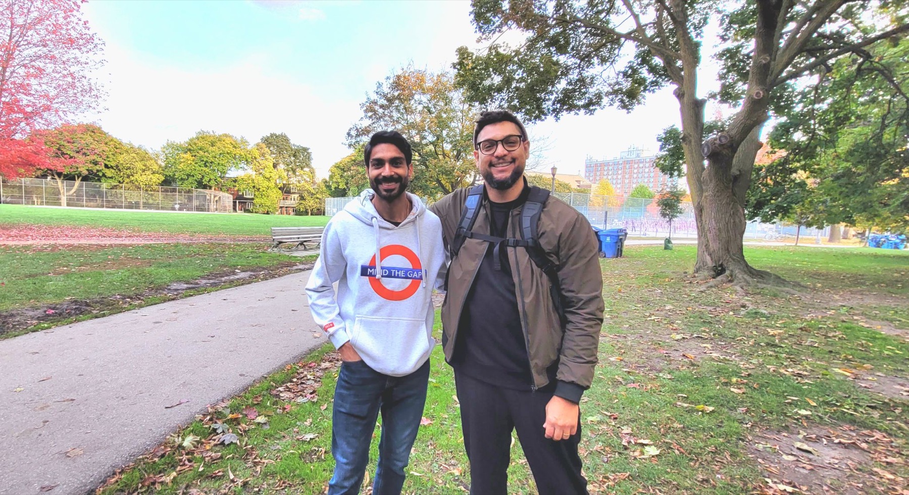 Christopher Miller and Arjit Singh standing together on a path in Trinity Bellwoods park in autumn