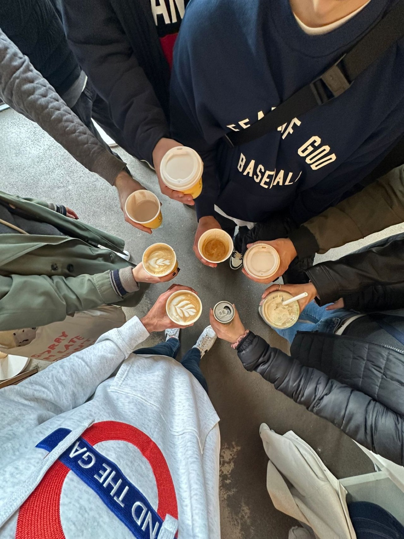 A DesignWalks group standing in a circle, holding their coffee cups together toward the centre